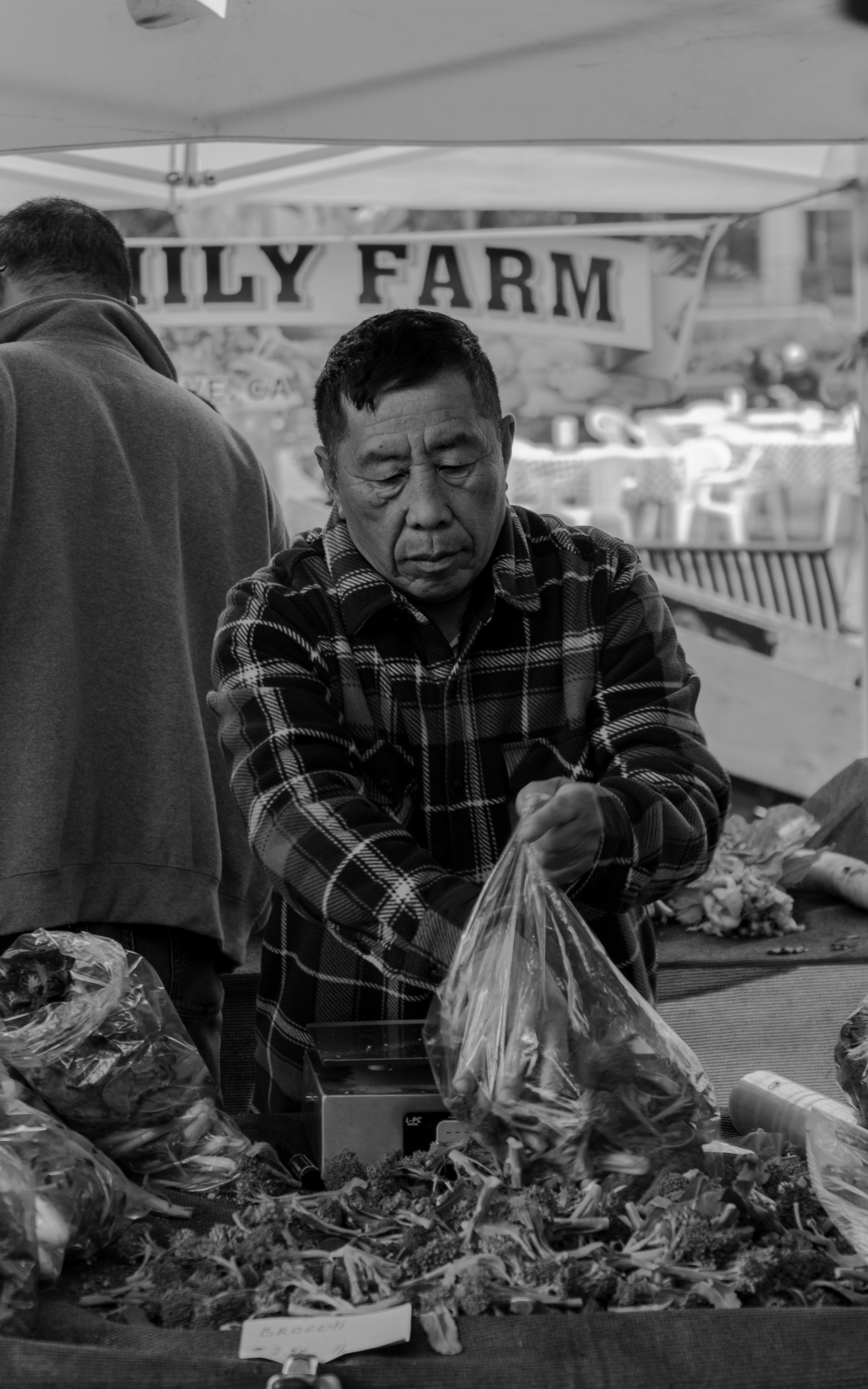 Graustufenfoto eines Mannes im karierten Hemd, der auf einem Stuhl sitzt