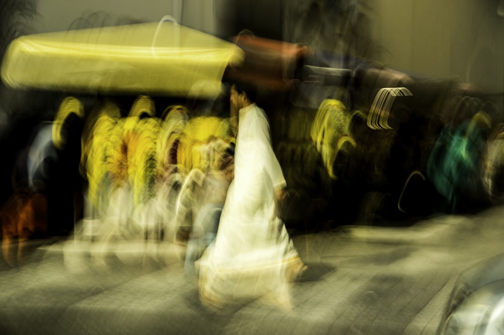 man in white thobe walking on street during night time