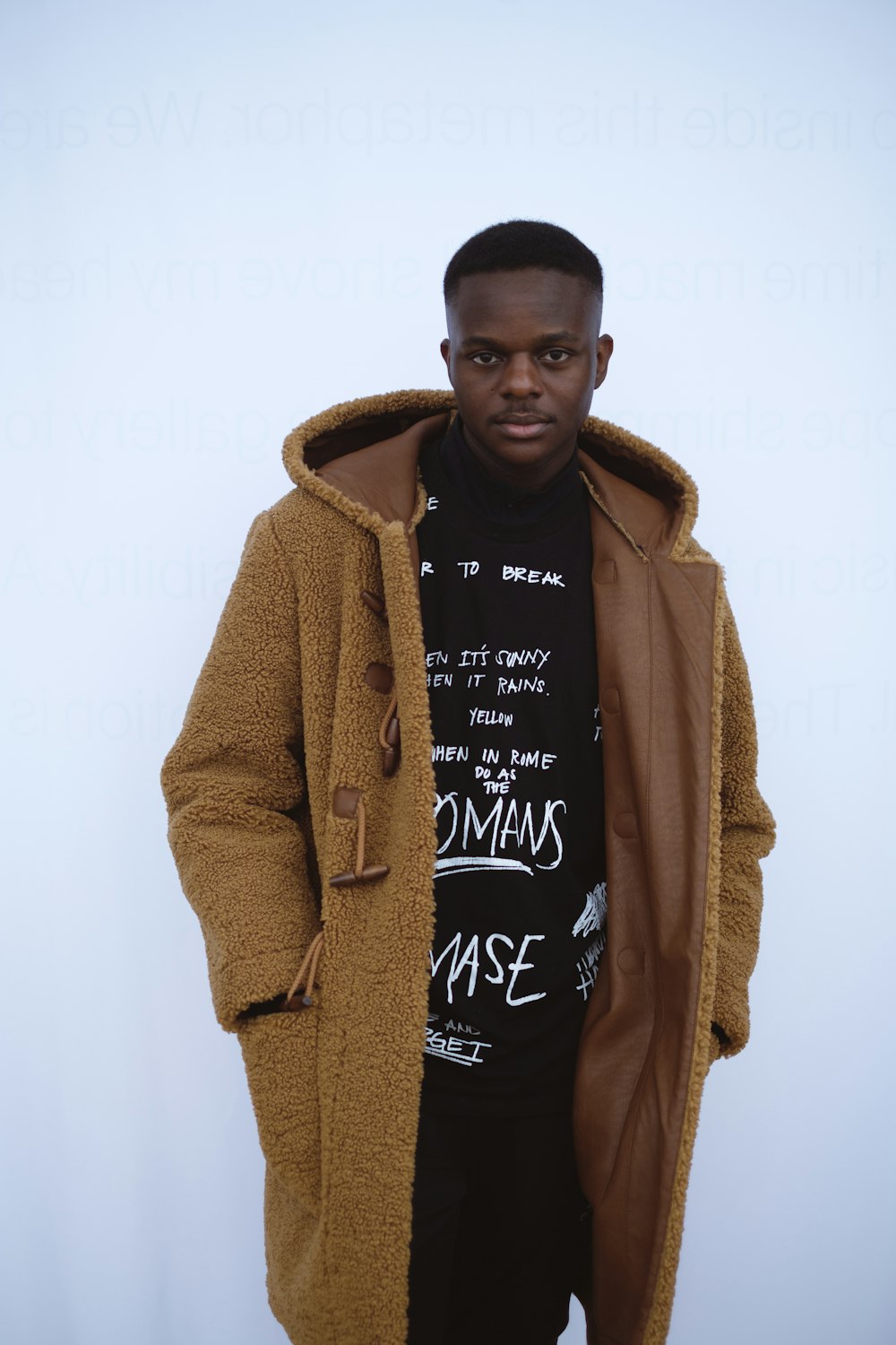 a man in a brown coat and a black t - shirt