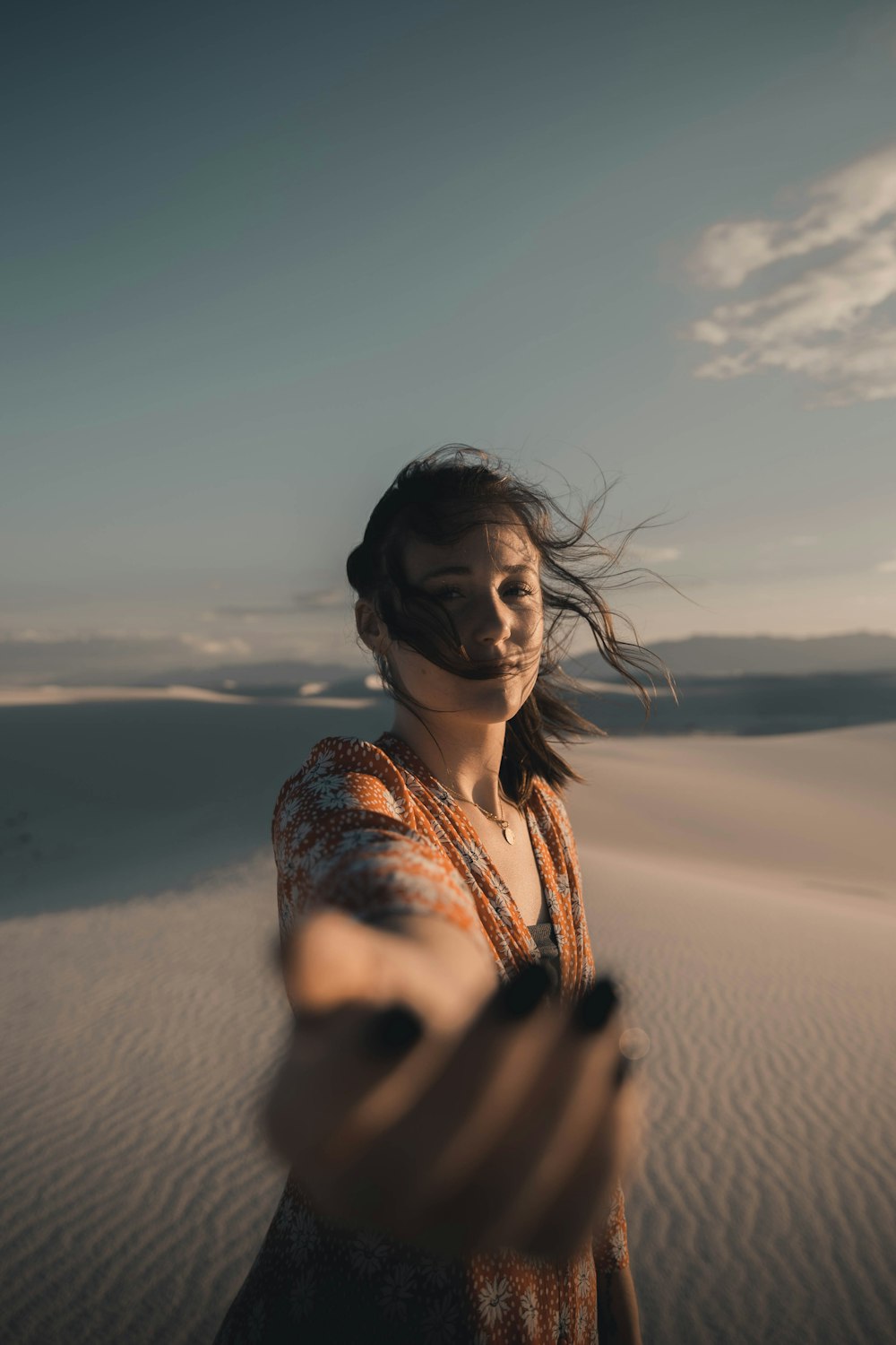 a woman standing in the sand holding a cell phone