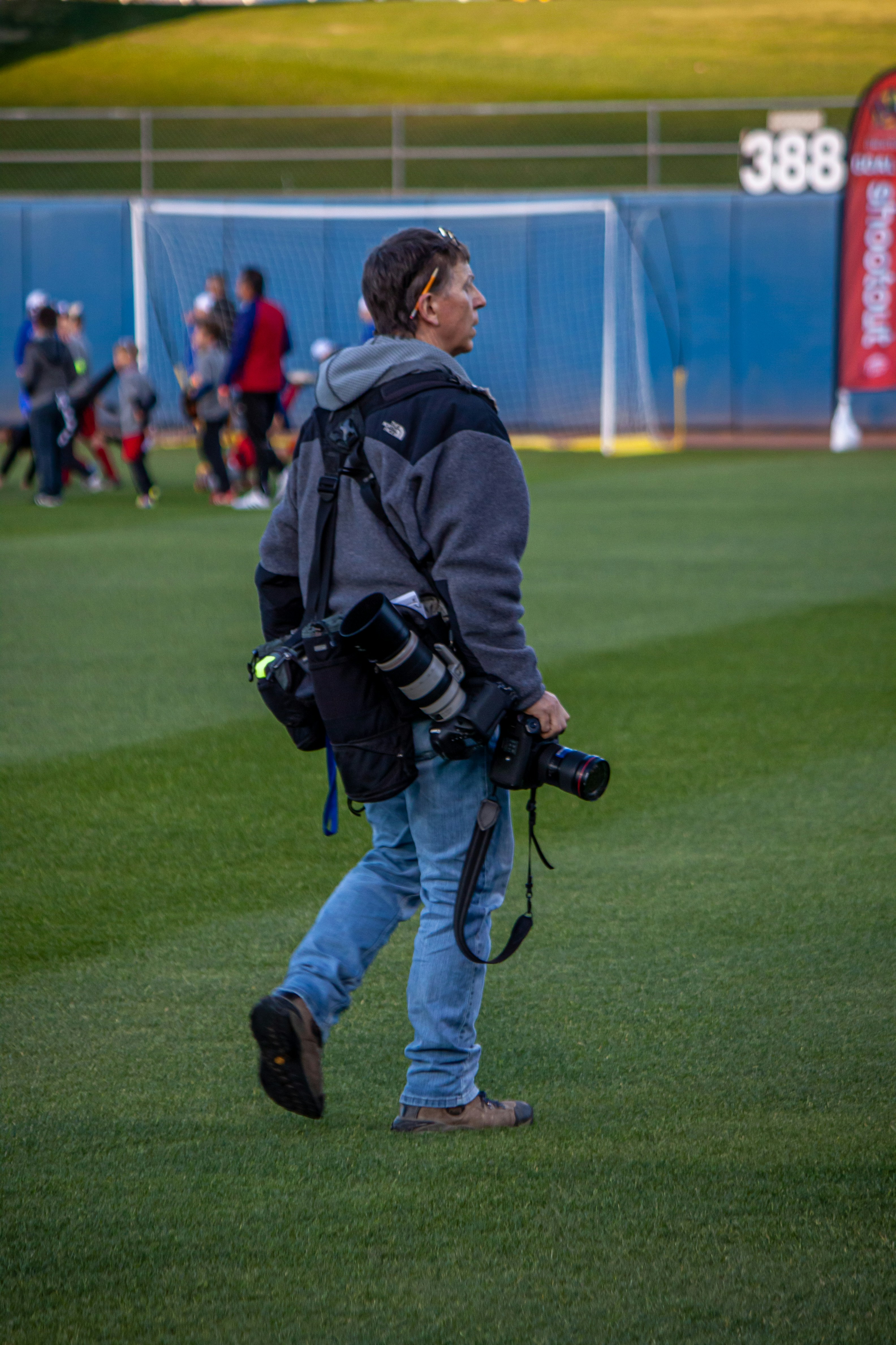 man in blue jacket and blue denim jeans walking on green grass field during daytime