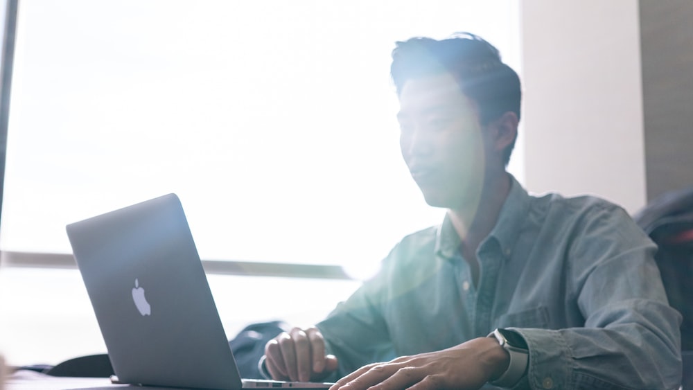 man in pink dress shirt using laptop computer