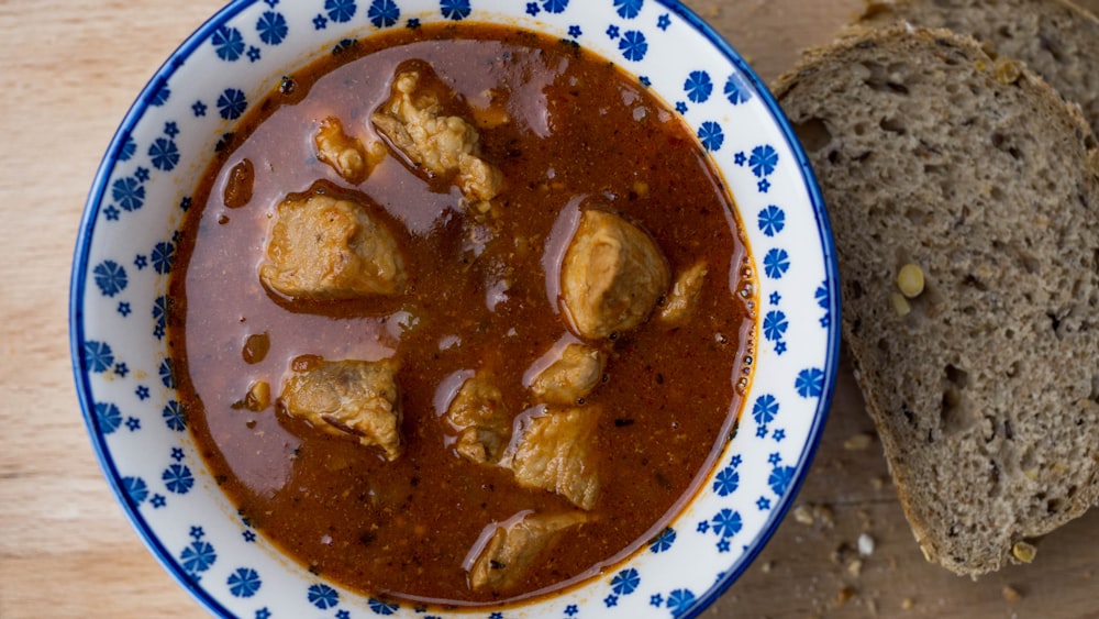 a bowl of stew with bread on a table