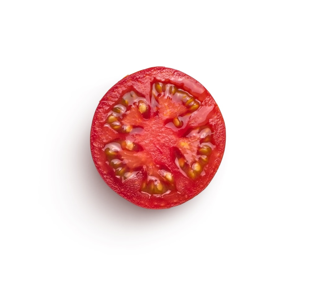 une tomate coupée en deux sur une surface blanche