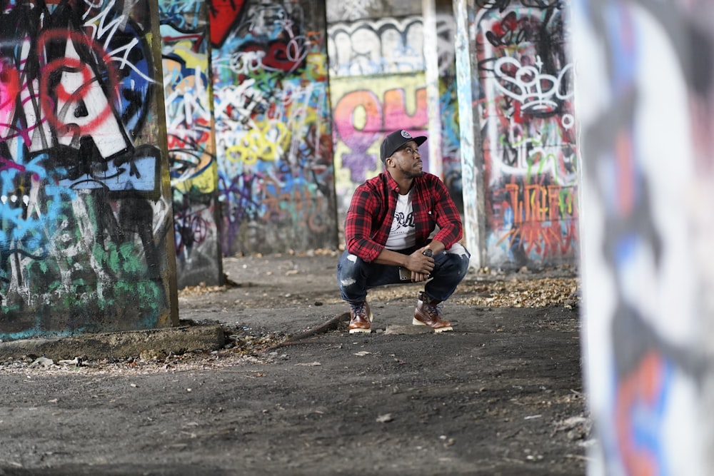 Homme en chemise à carreaux rouge et bleu et jean bleu assis sur un mur en  béton photo – Photo Person Gratuite sur Unsplash