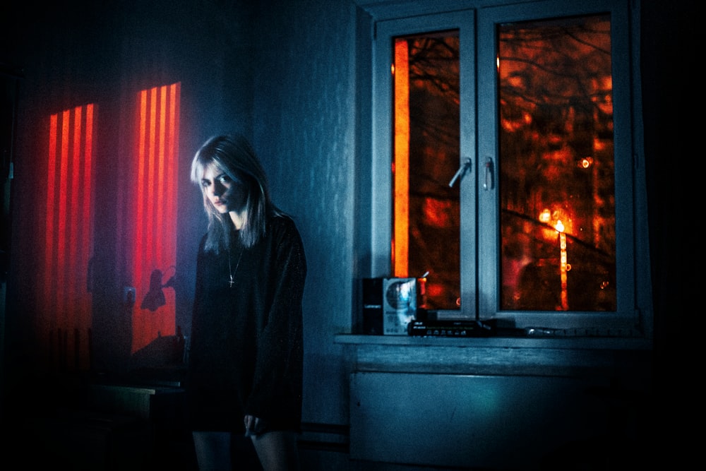 woman in black jacket standing beside window