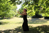 A serene woman practicing gentle movement outdoors surrounded by mossy greenery.