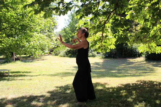 A serene studio space with Heng Hu guiding a client through a slow, focused qigong movement.