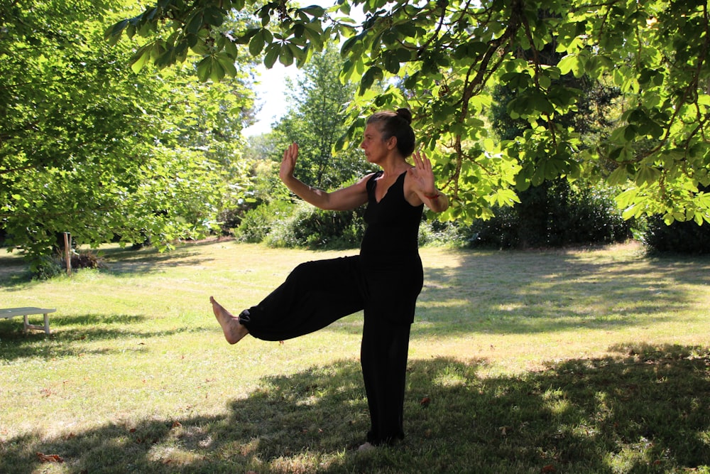 woman in black sleeveless dress standing under green tree during daytime