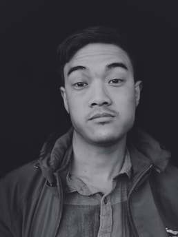 A sharp, minimalist business headshot featuring a person in smart attire against a clean white background.