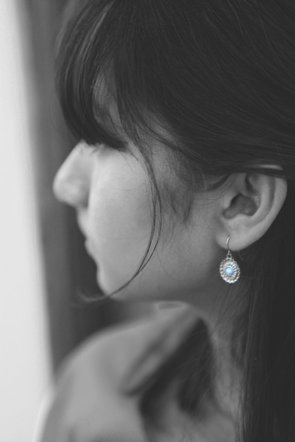 grayscale photo of woman wearing silver diamond stud earring