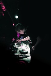 Artist performing live in a dark club with intense techno lighting.