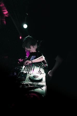 A DJ performing energetically in a vibrant club setting.