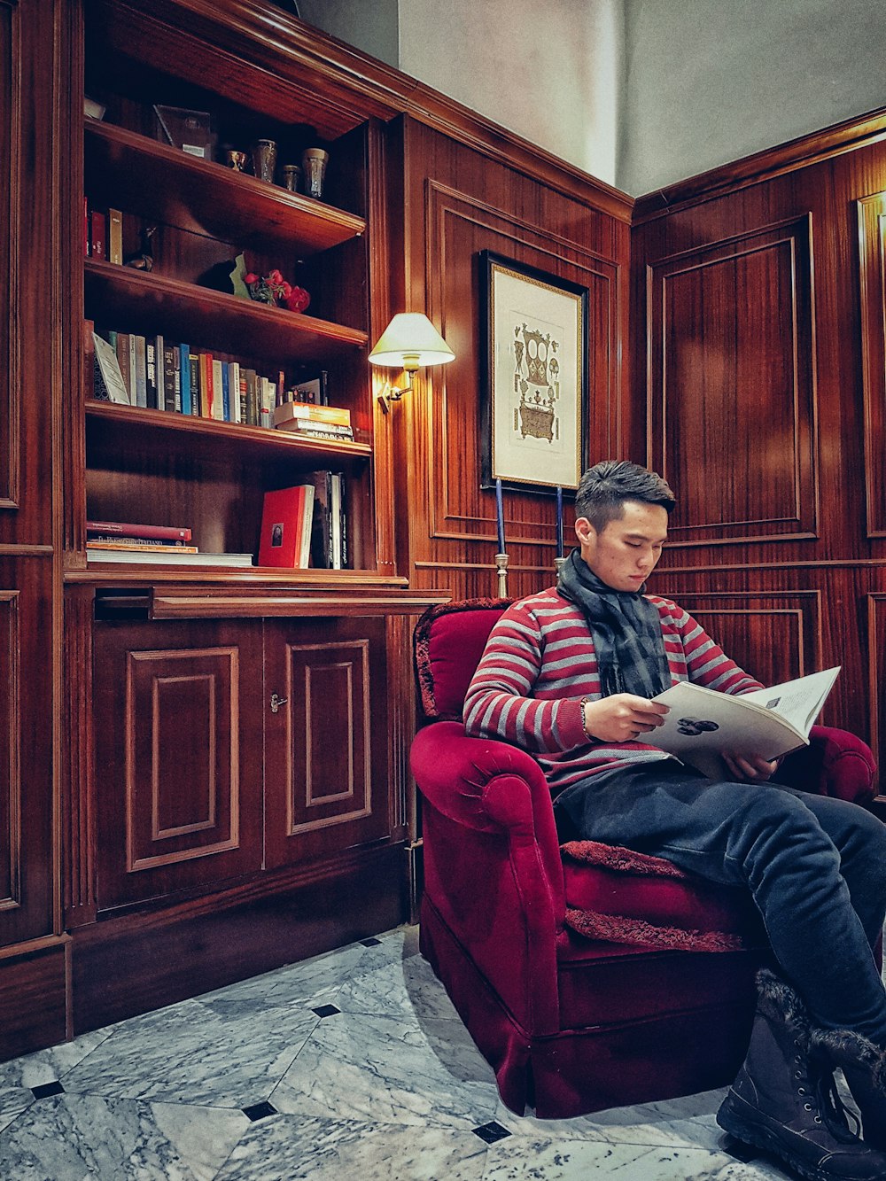 man in black and red striped long sleeve shirt sitting on red sofa chair