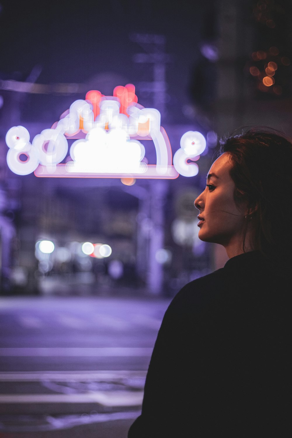 woman in black shirt standing near glass window during night time