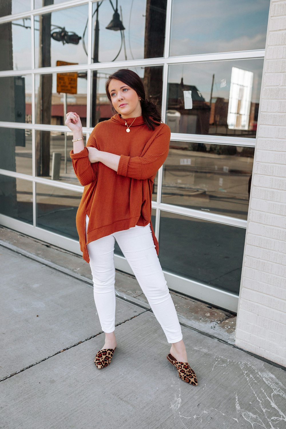 a woman standing on a sidewalk in front of a building