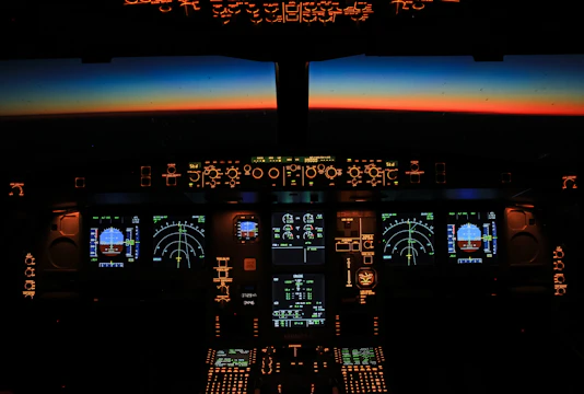 A cockpit view at dawn, instruments glowing softly against a navy sky.