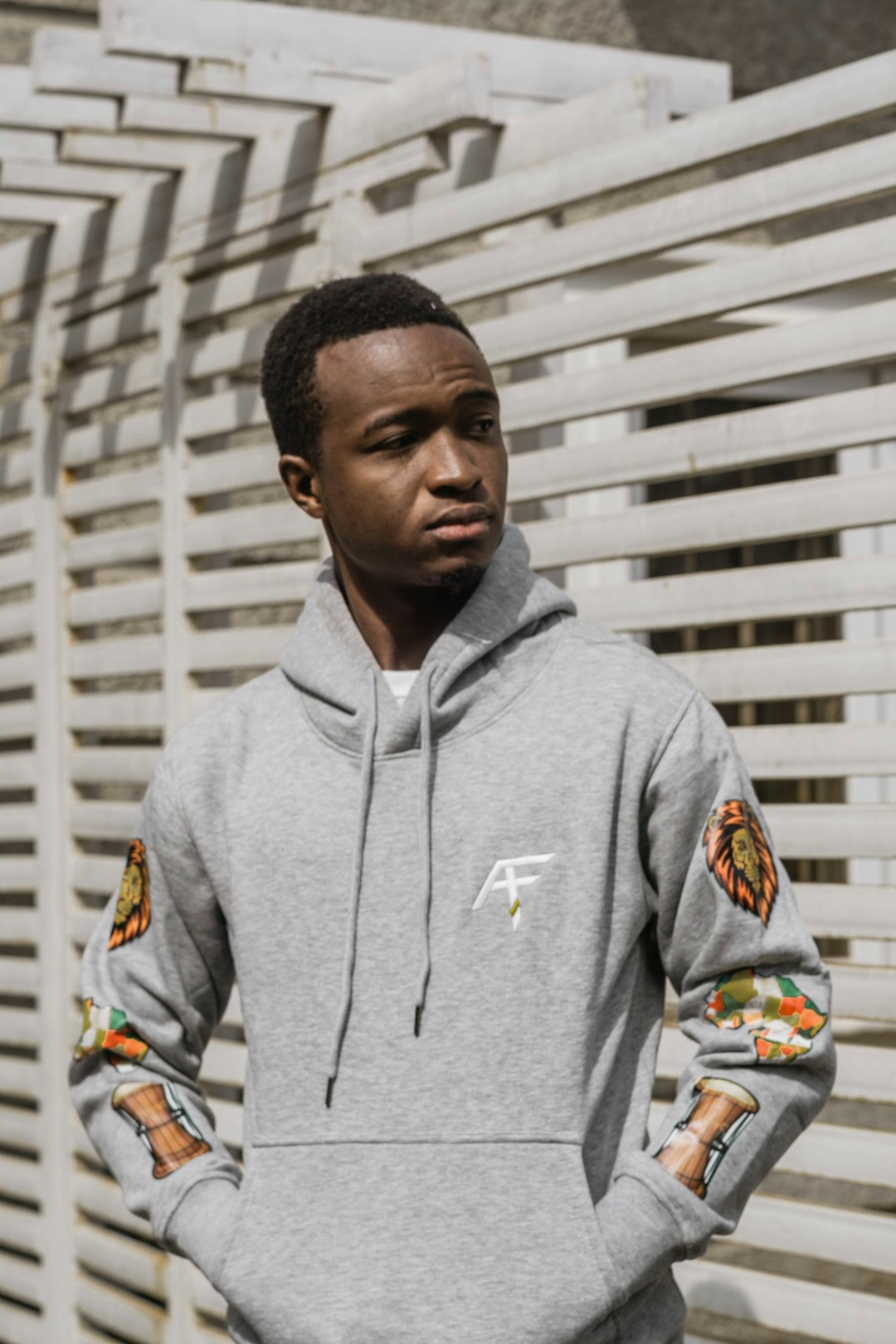 man in gray pullover hoodie standing near white wall during daytime