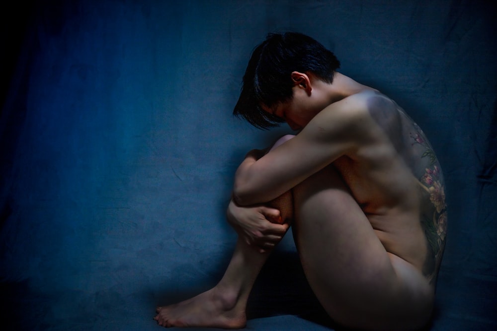 femme aux seins nus assise sur un textile bleu
