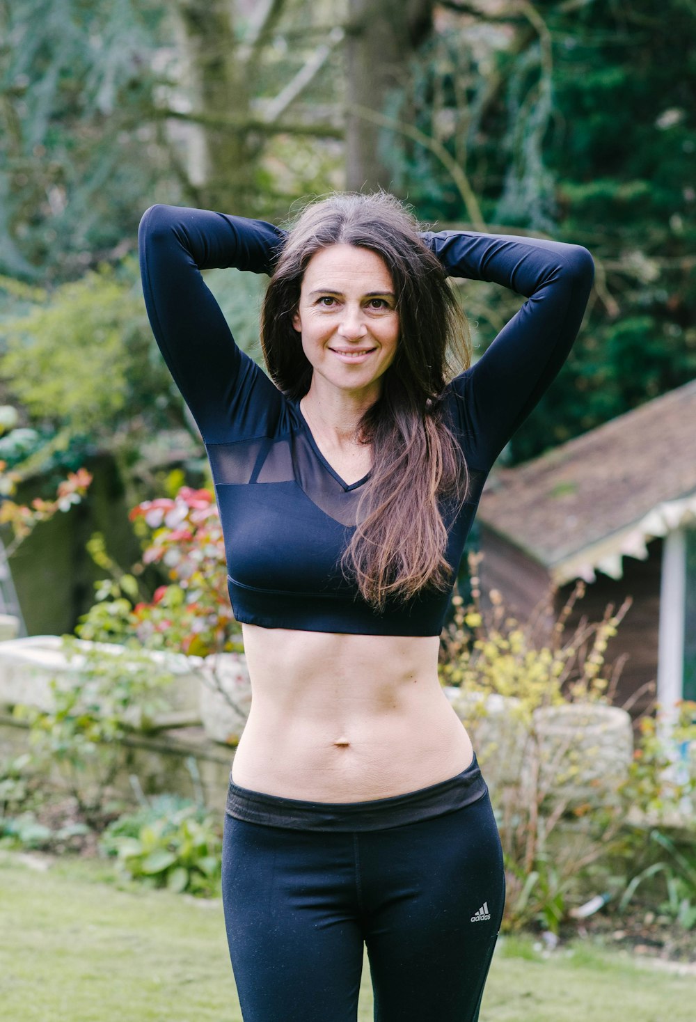 woman in black crop top and blue denim jeans standing on brown wooden bridge during daytime