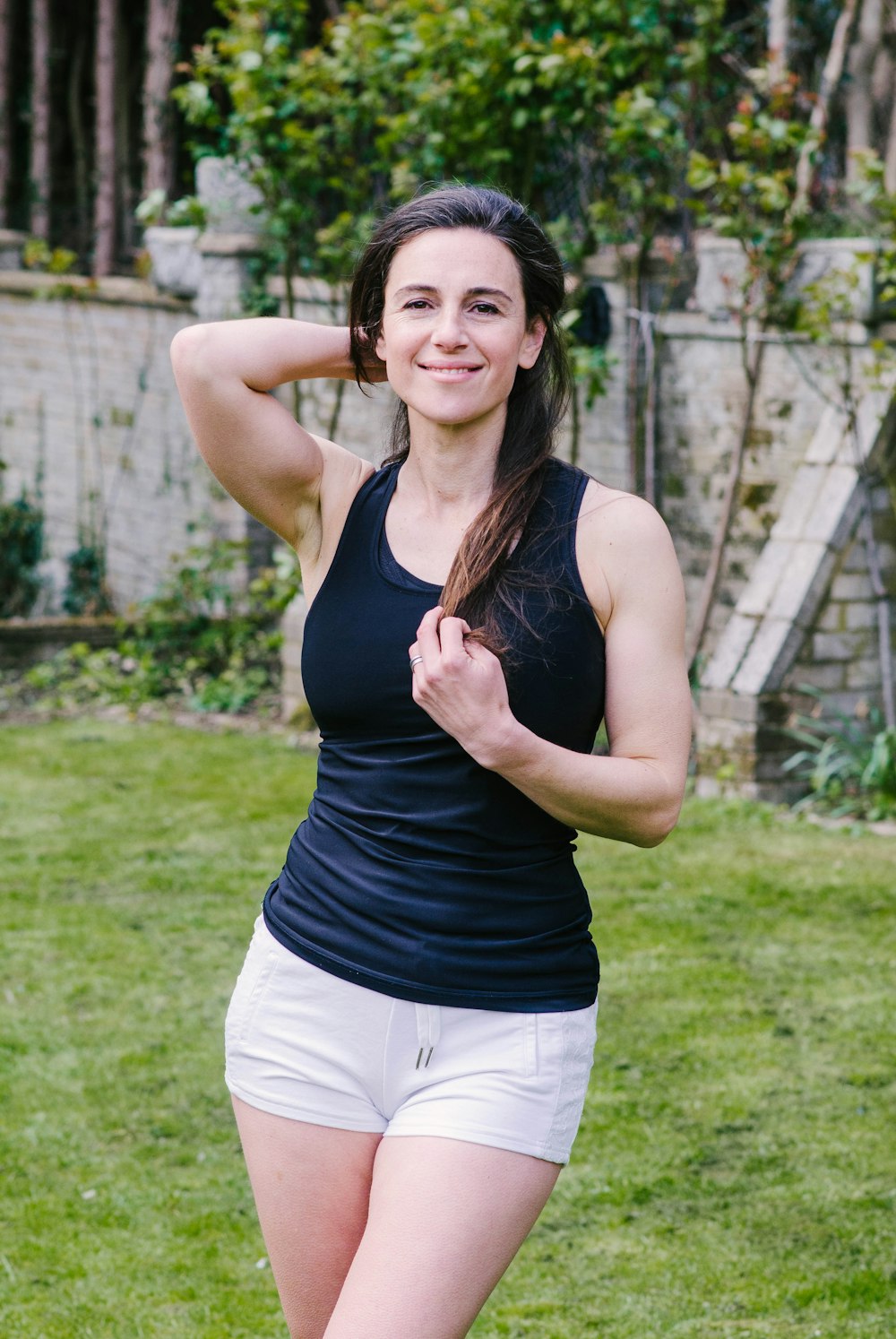 woman in black tank top and white shorts standing on green grass field during daytime