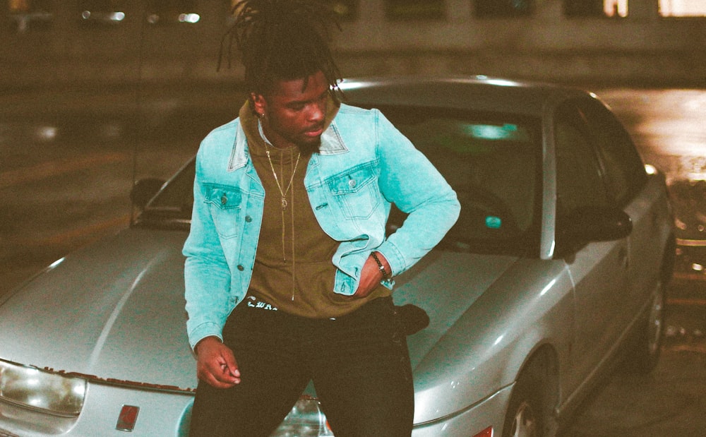 man in blue dress shirt and black pants sitting on white car