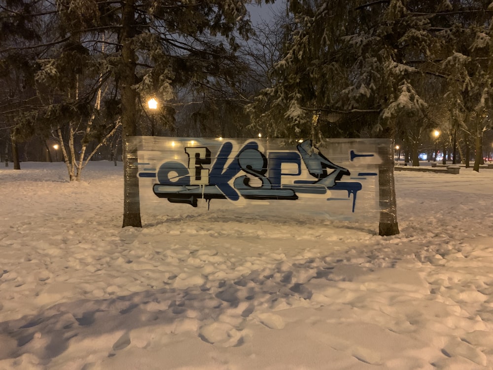 snow covered bench near trees during daytime