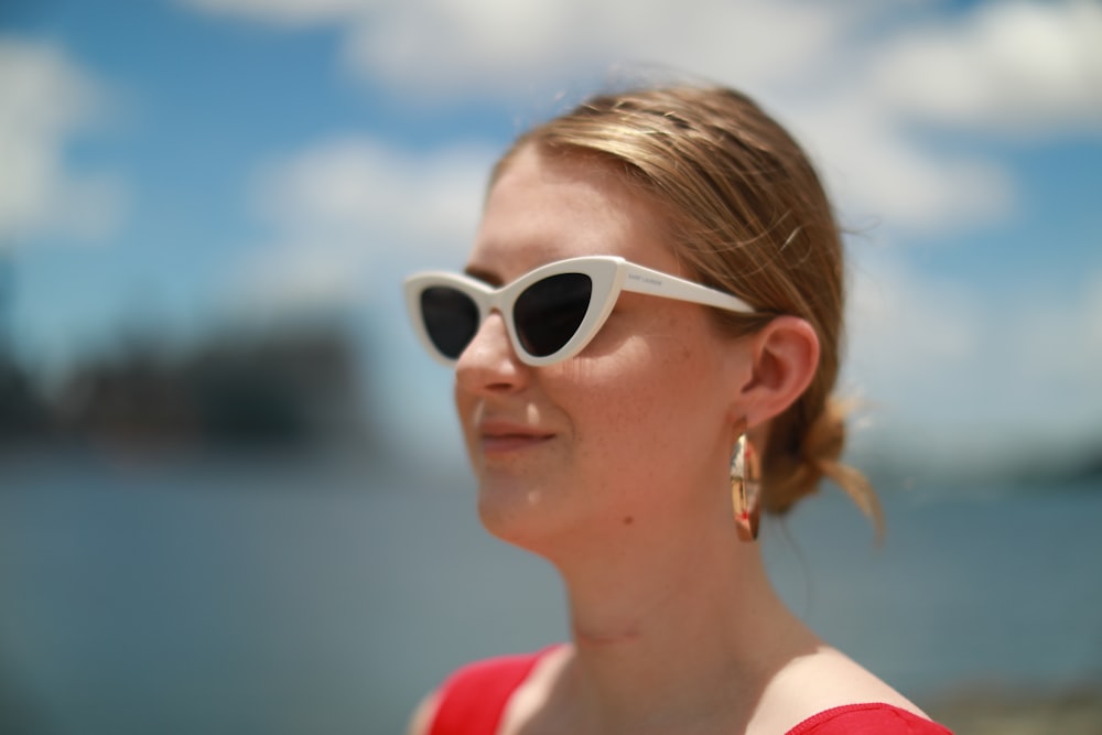 mulher em óculos de sol armacionados brancos e regata vermelha e branca