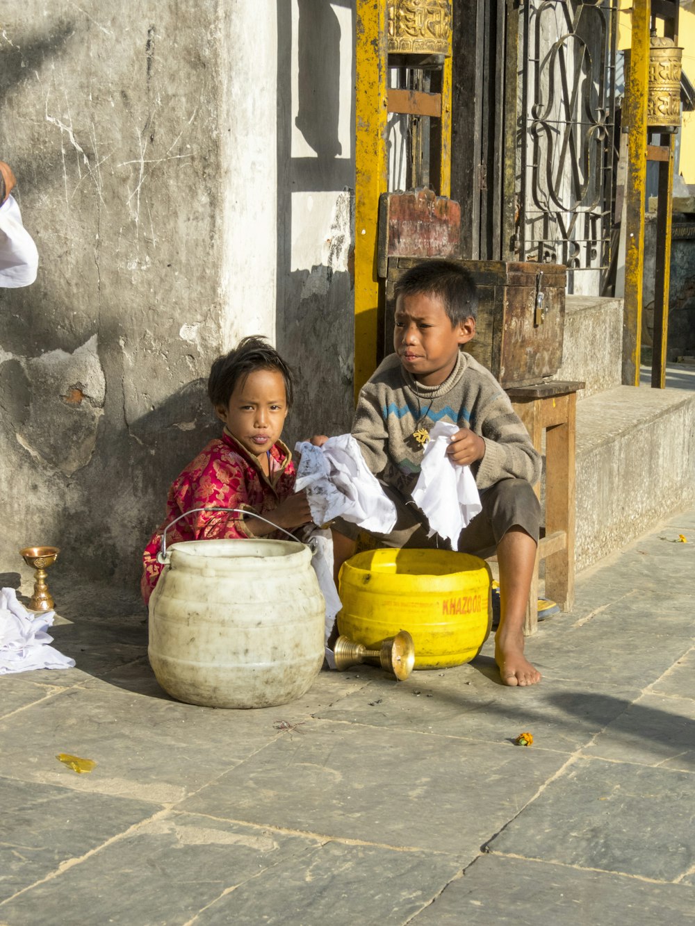 girl in white long sleeve shirt sitting beside yellow plastic bucket