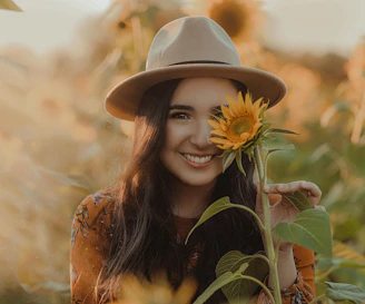 A radiant woman smiling warmly in a sunlit Belgian countryside field.