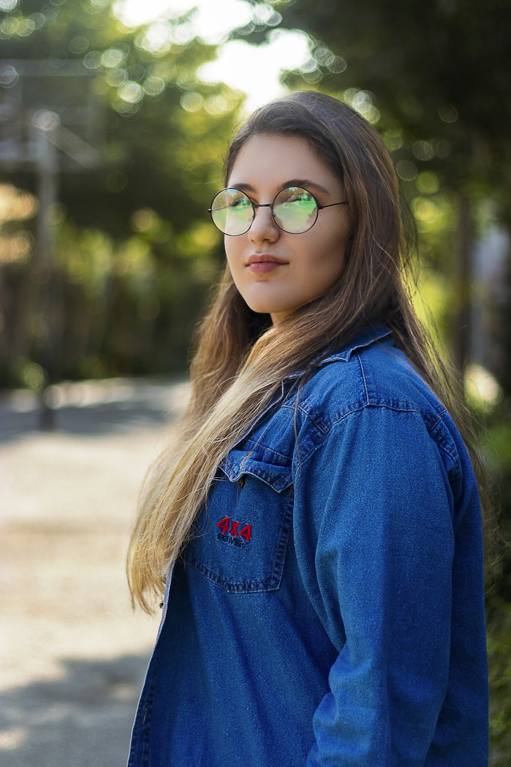 girl in blue denim jacket wearing green framed sunglasses