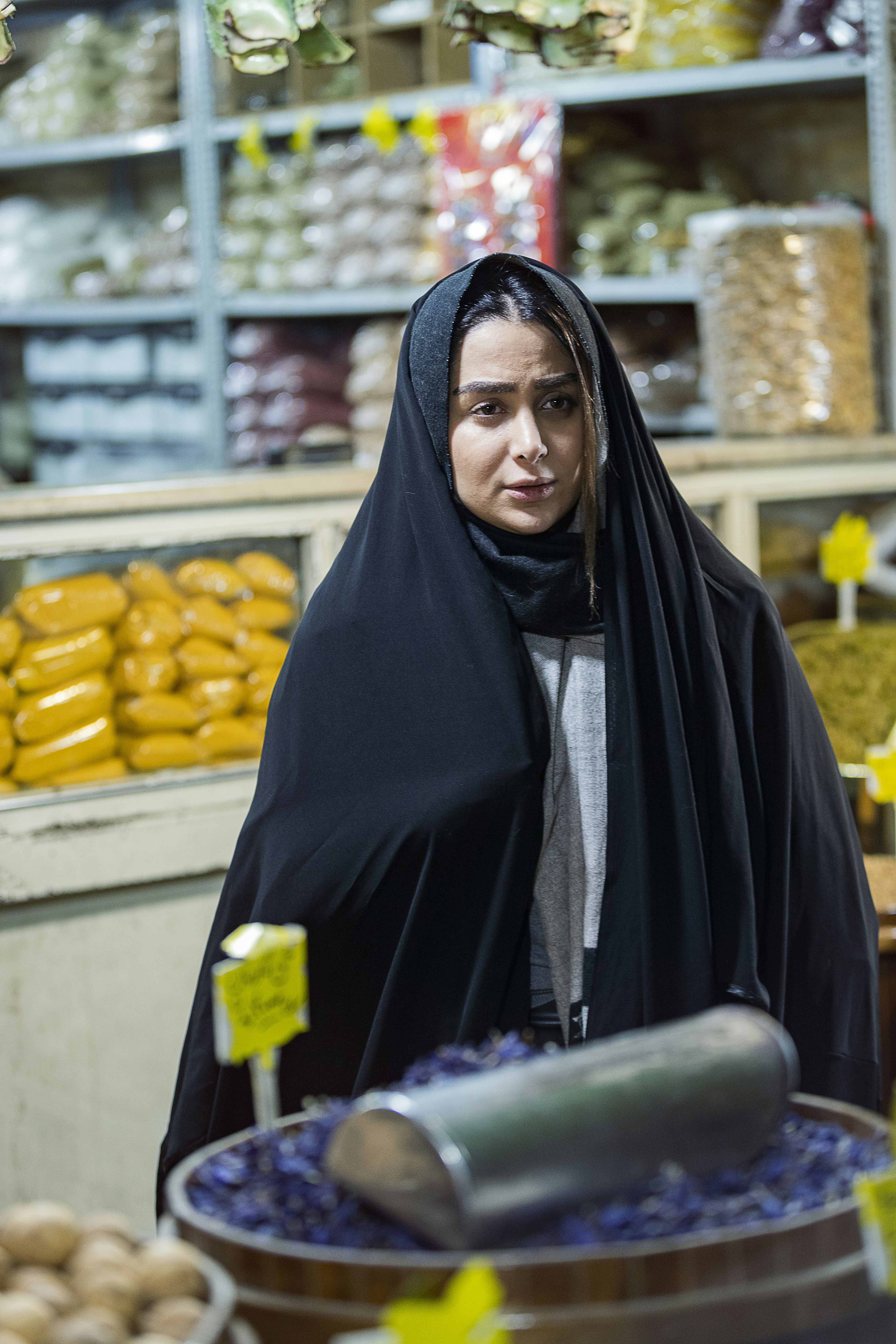 Wanita berhijab hitam memegang botol plastik hijau