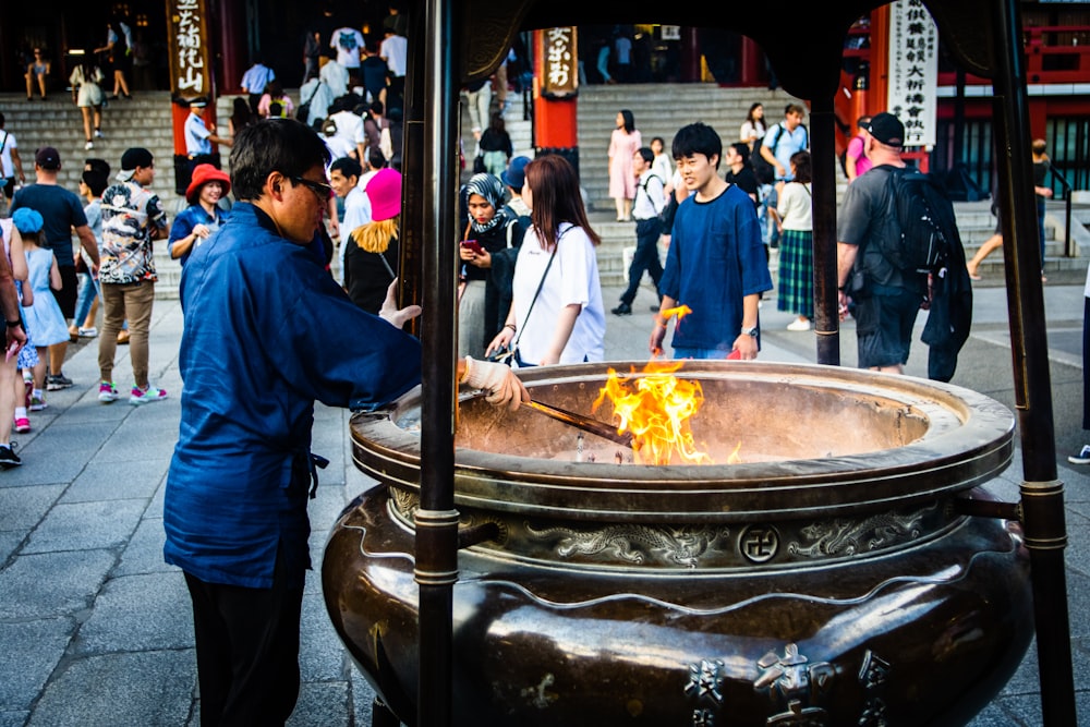 homme en chemise bleue debout devant le feu