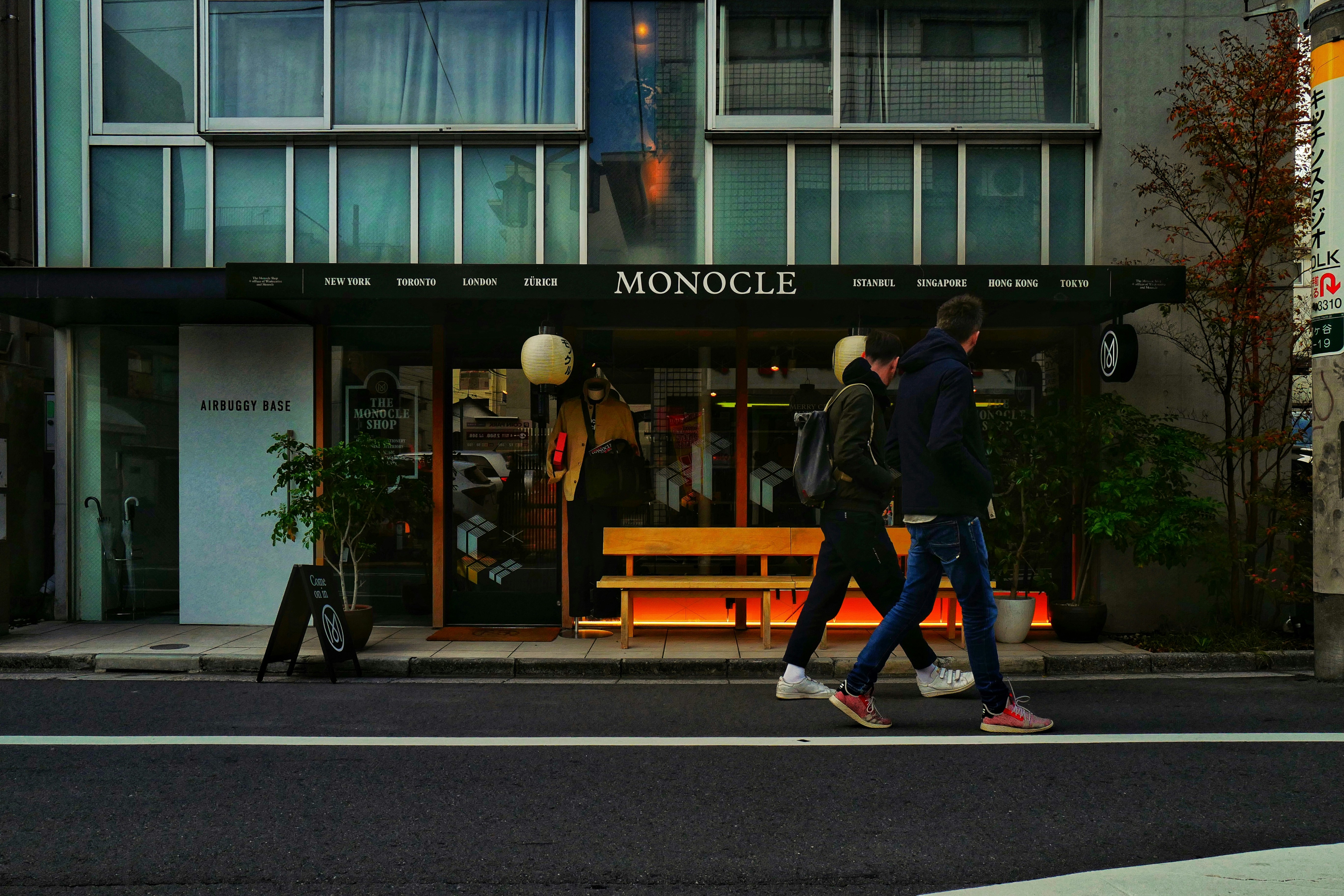 man in black jacket and blue denim jeans walking on sidewalk during daytime