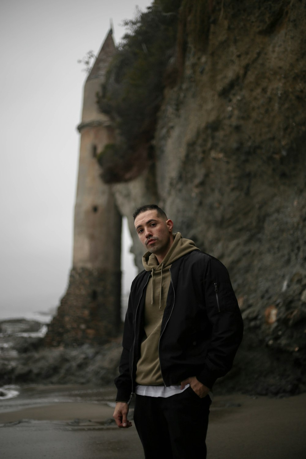 man in black jacket standing near brown concrete wall during daytime