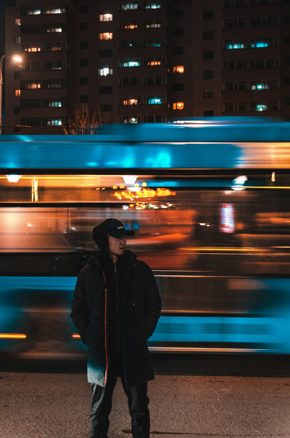 man in black jacket standing in front of building during night time