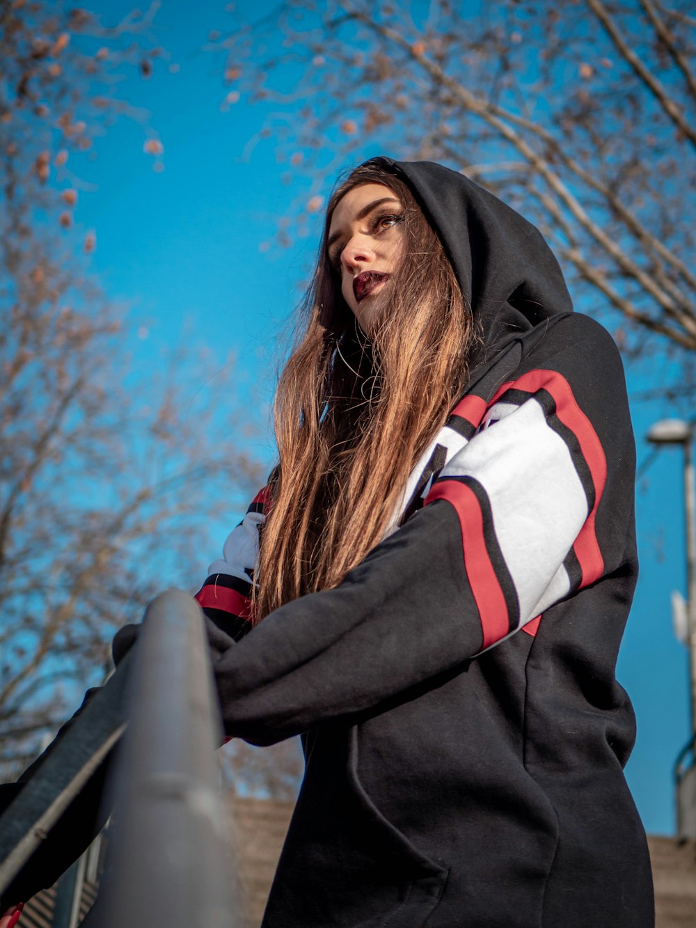 woman in black white and red jacket standing near gray metal fence during daytime