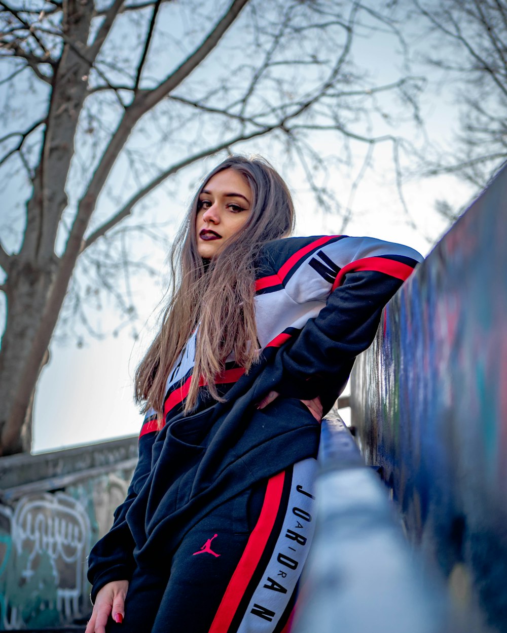 woman in black white and red jacket standing on bridge during daytime