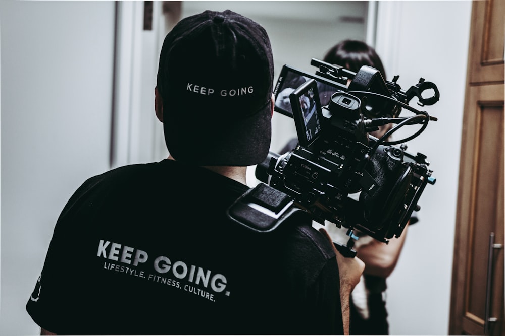 man in black crew neck t-shirt holding black dslr camera