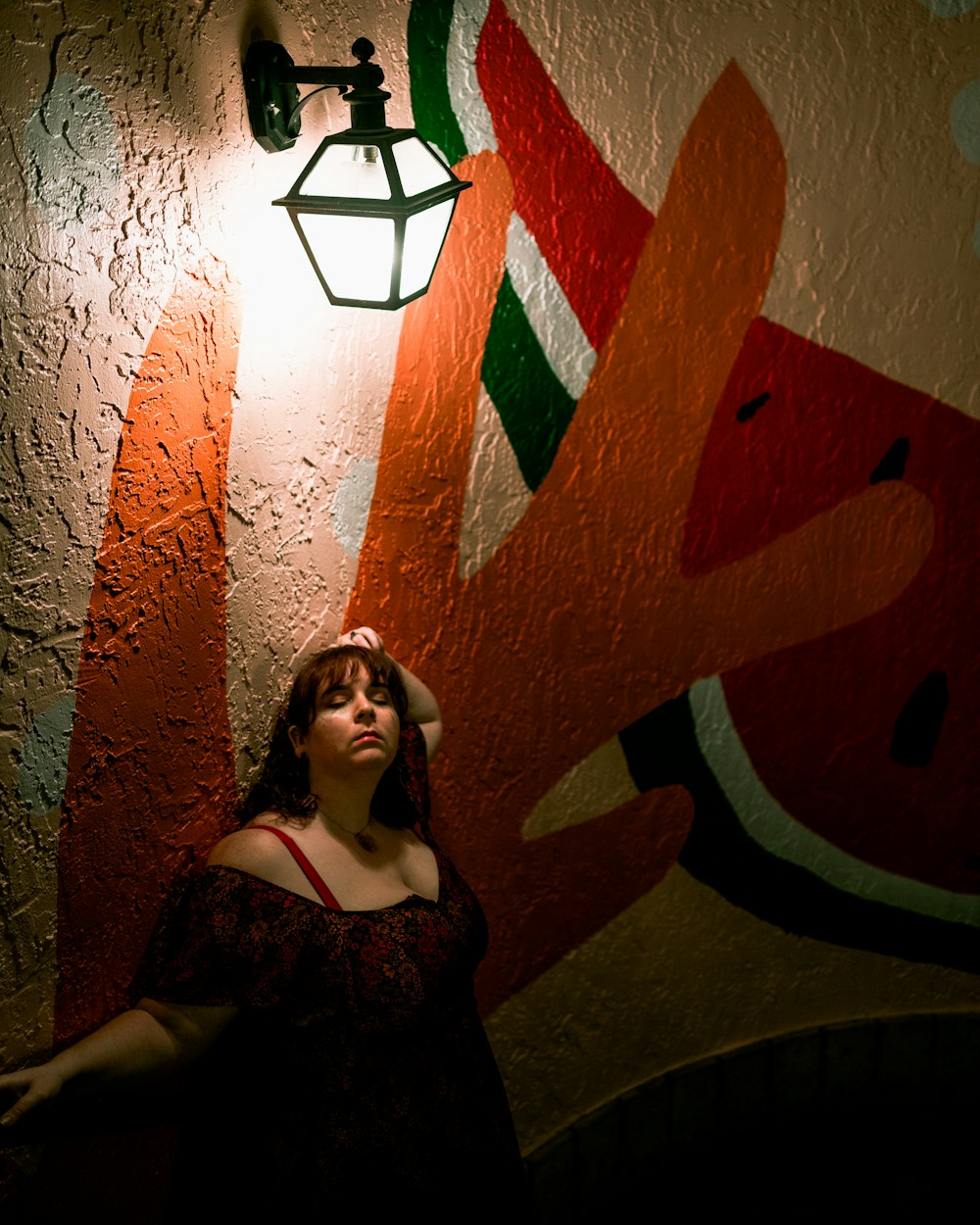 woman in black floral dress leaning on wall