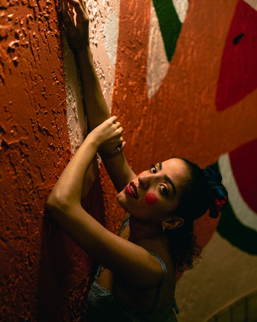 woman in black tank top leaning on orange wall