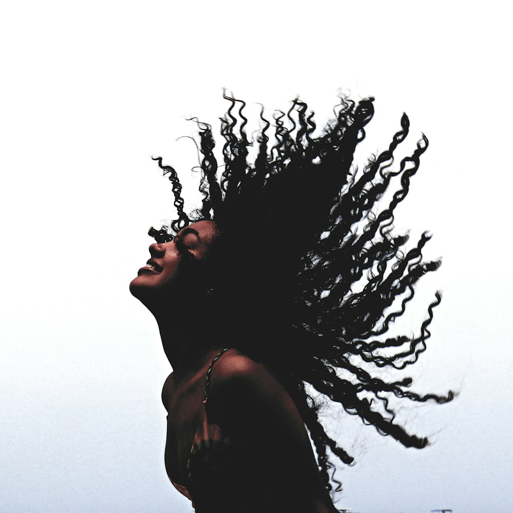 woman in black tank top standing beside leafless tree during daytime