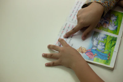 Hands of a parent and child working together on an educational activity book.