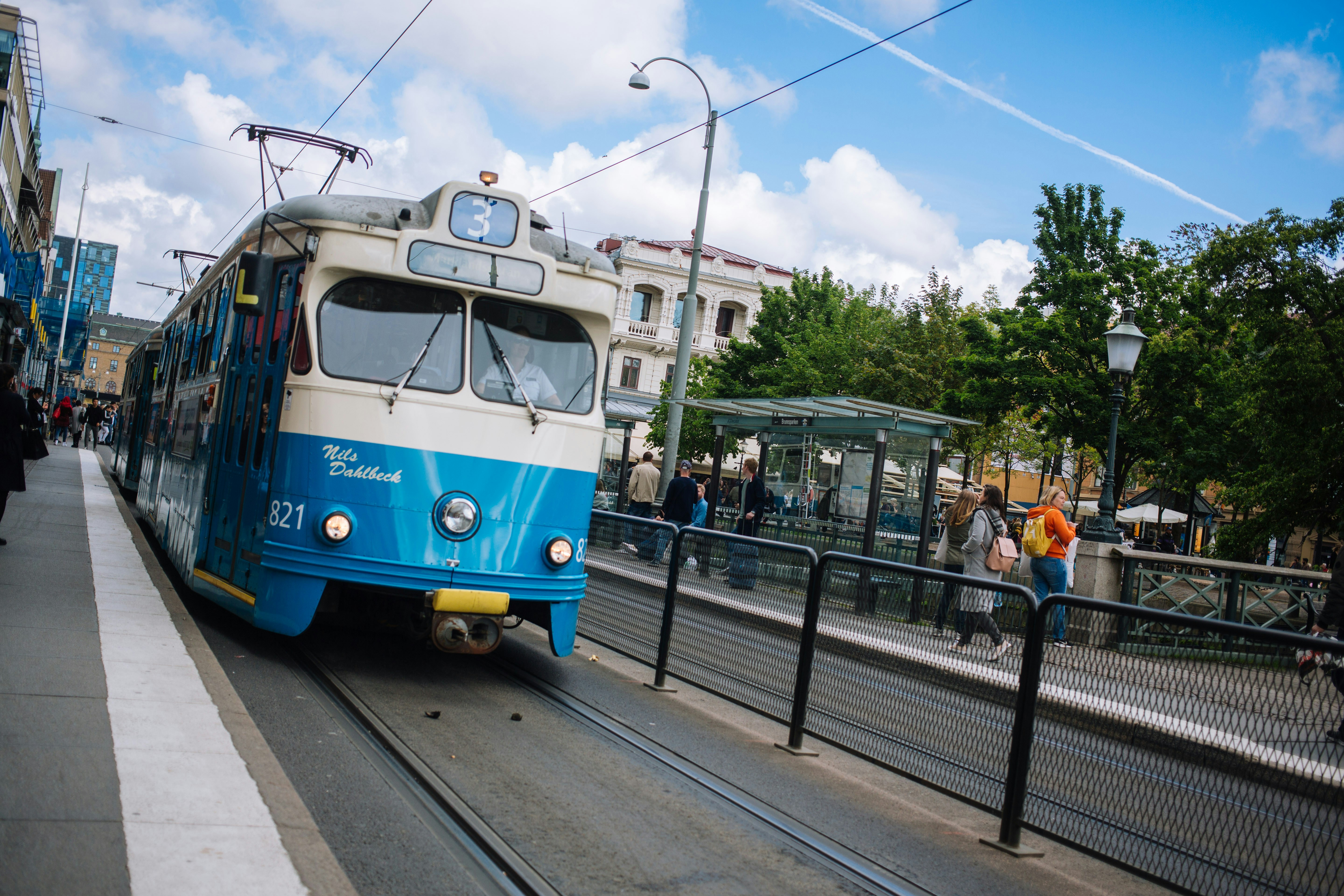 people walking on street near blue and white tram during daytime