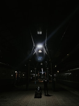 A cozy backpack resting on a worn wooden bench at a bustling train station, with a cityscape blurred in the background.