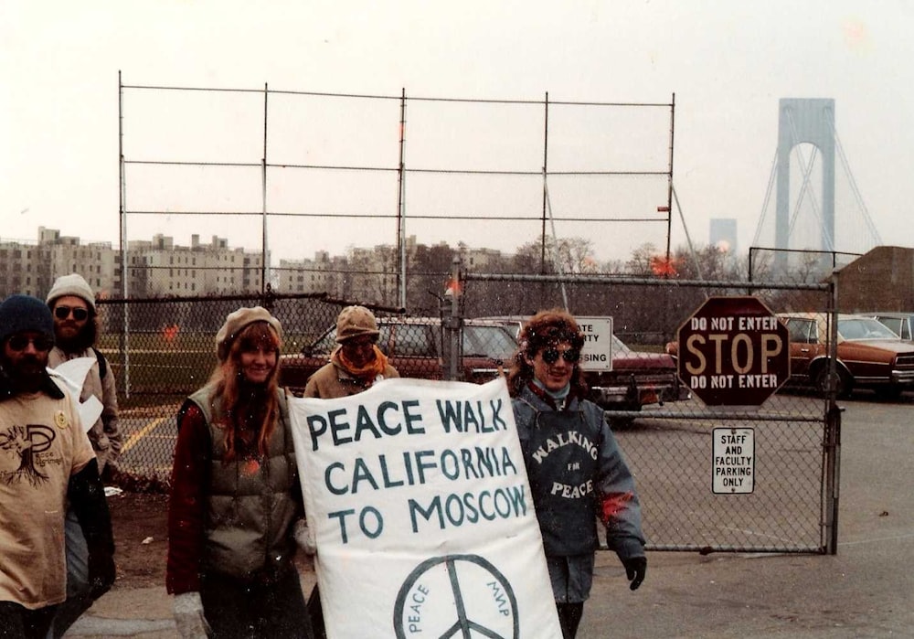 man in black jacket holding white and blue banner