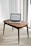 A laptop is placed on a small wooden table in a room with light-colored carpet and vertical blinds. The laptop screen displays a webpage titled 'Interactive RFID', indicating a focus on technology.
