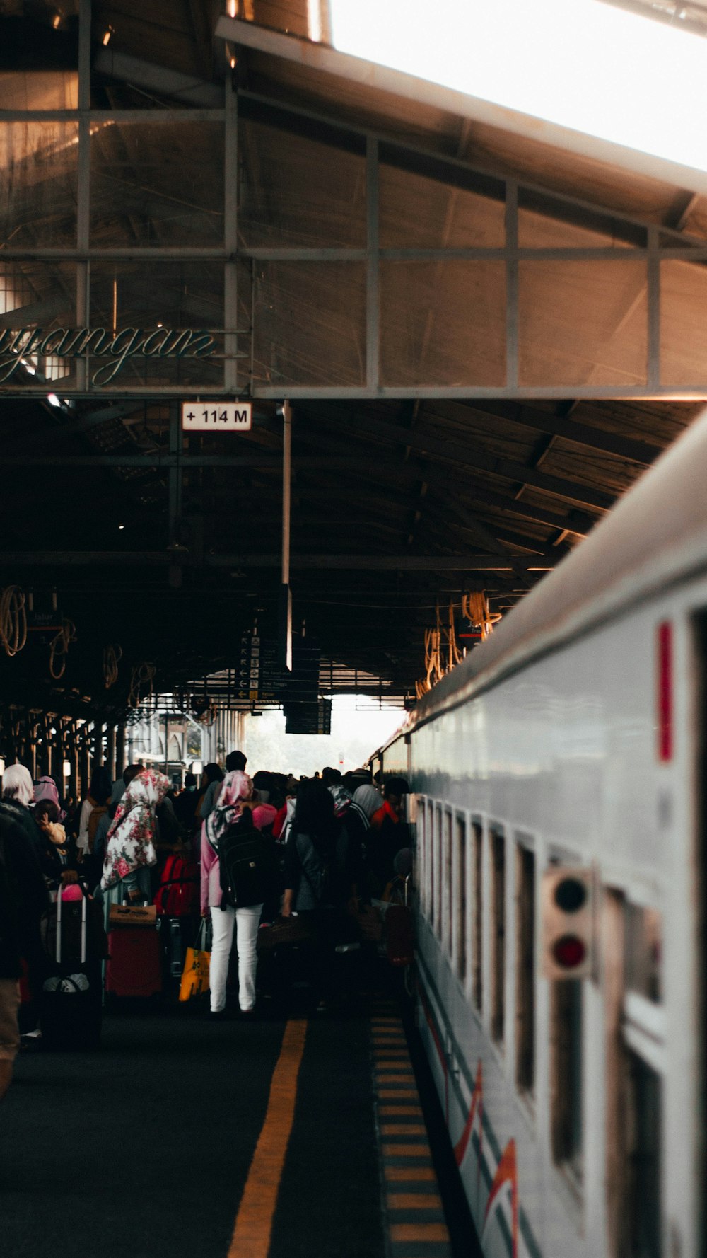 people in red and black jackets standing on train station during daytime