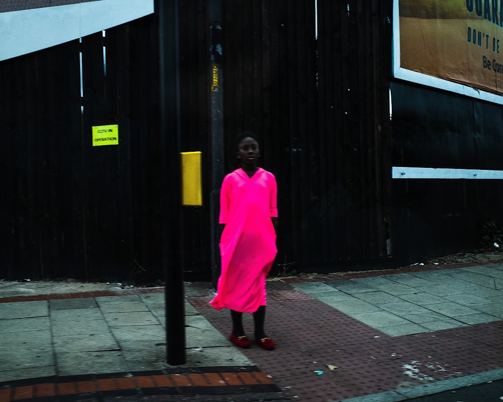 woman in pink robe standing on sidewalk
