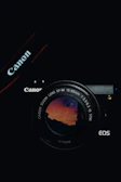 A sleek modern mirrorless camera with a colorful lens reflecting a sunset.